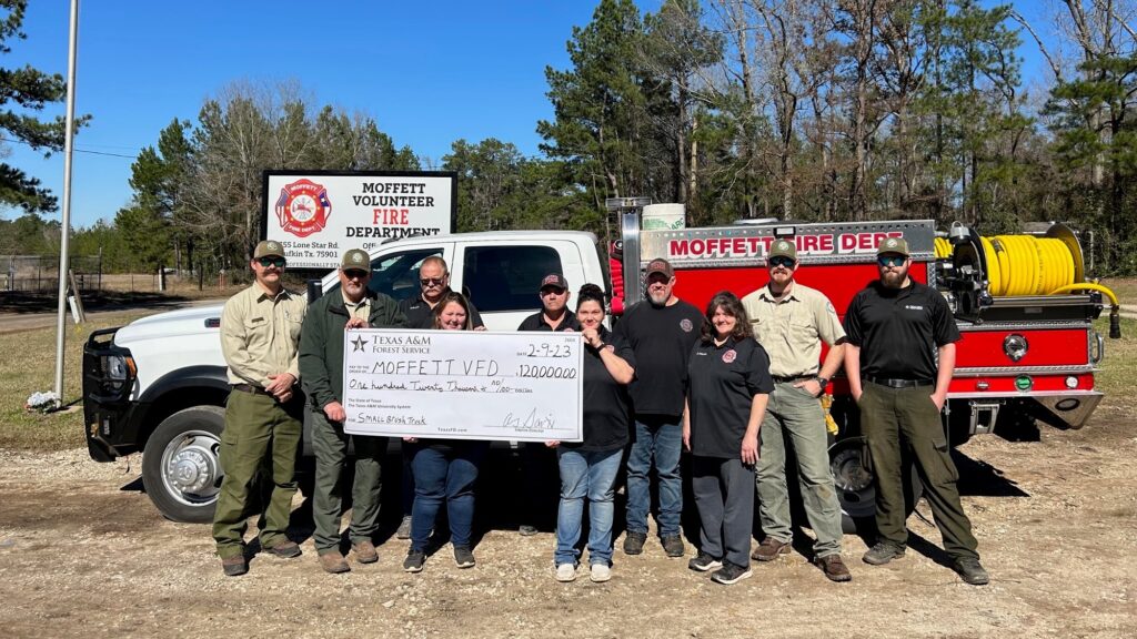 Moffett Volunteer Fire Department members and Texas A&M Forest Service representatives pose with a $120,000 grant check in front of a fire truck.