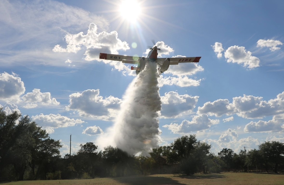 Fixed-wing aircrapf drops water over trees