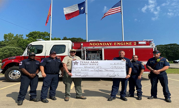 Noonday Fire Department Holds Big Check in Front of Fire Truck