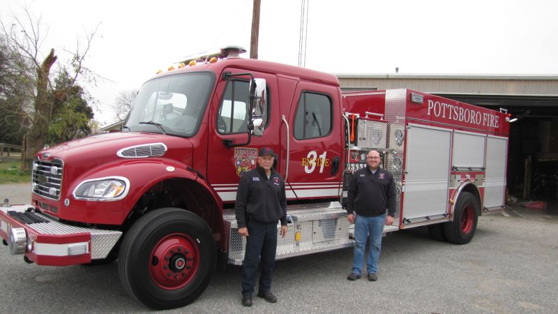 New Pottsboro Fire Truck shown from side with Pottsboro Chief and Assistant Chief standing in front of it.