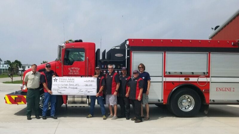 Surfside VFD holding big check with Forest Service personnel in front of their fire truck
