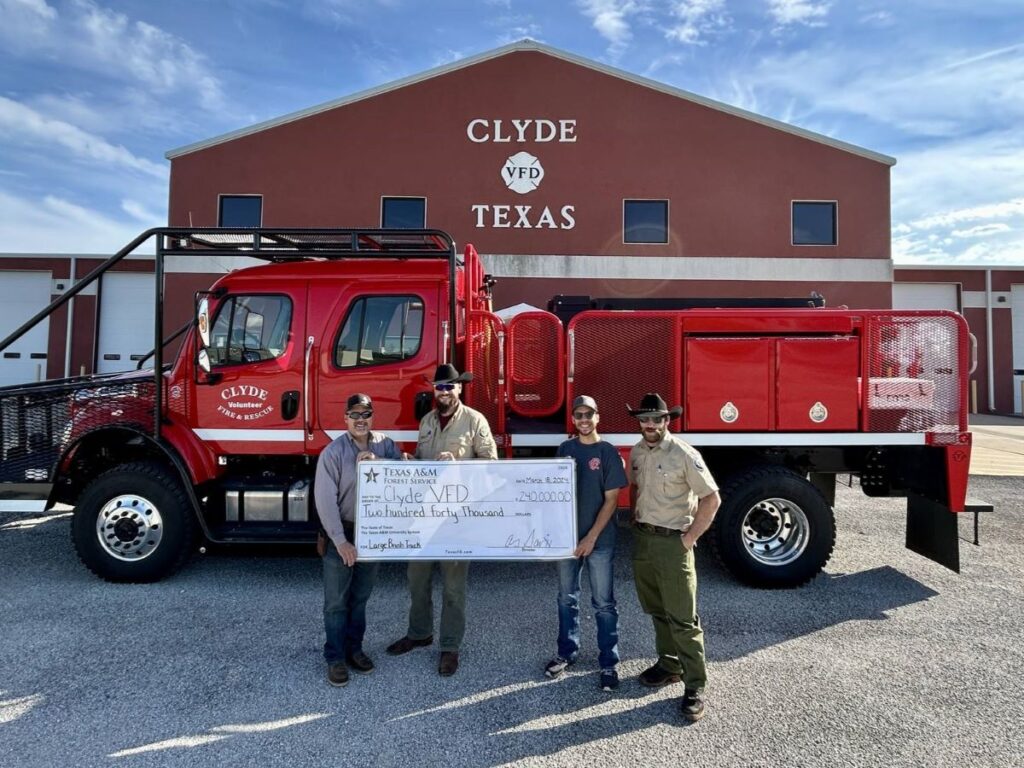 Grupo con un gran cheque frente al camión de bomberos