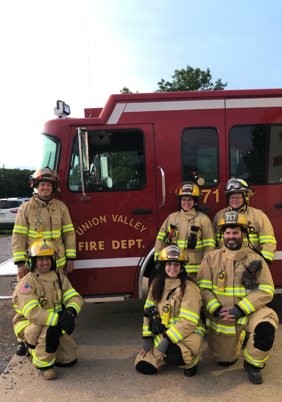Firefighters in gear posing in front of fire truck