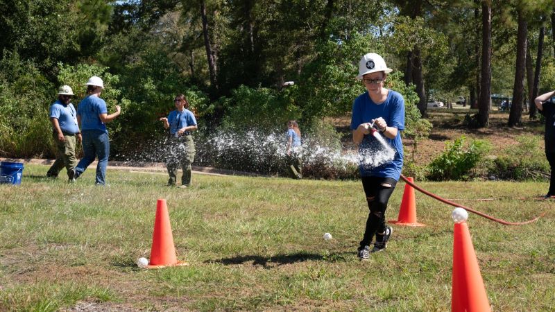 Girl spraying water hose at cones