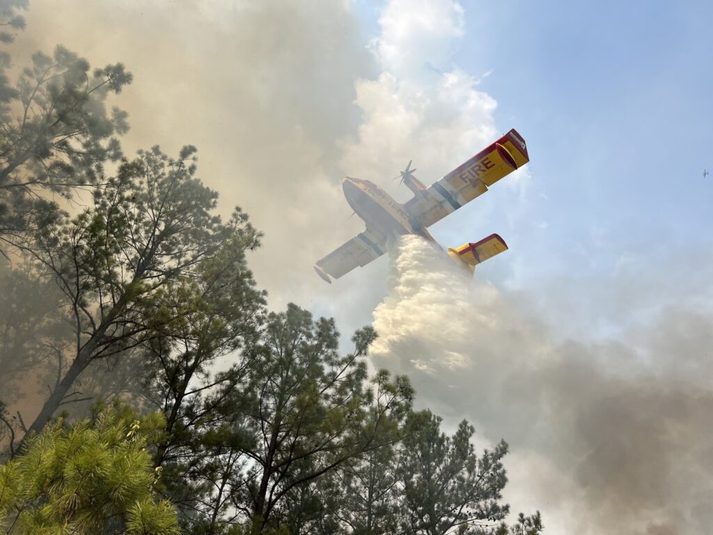 Super scooper airplane over trees and smoke