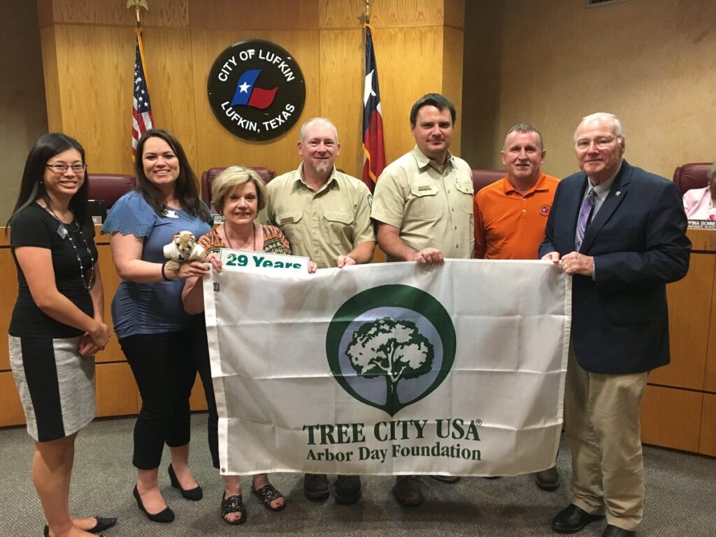 An image of people holding up a tree city arbor day foundation flag in front of them