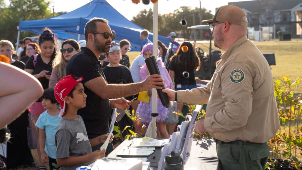 Forester handing out tree seedling to man and his family