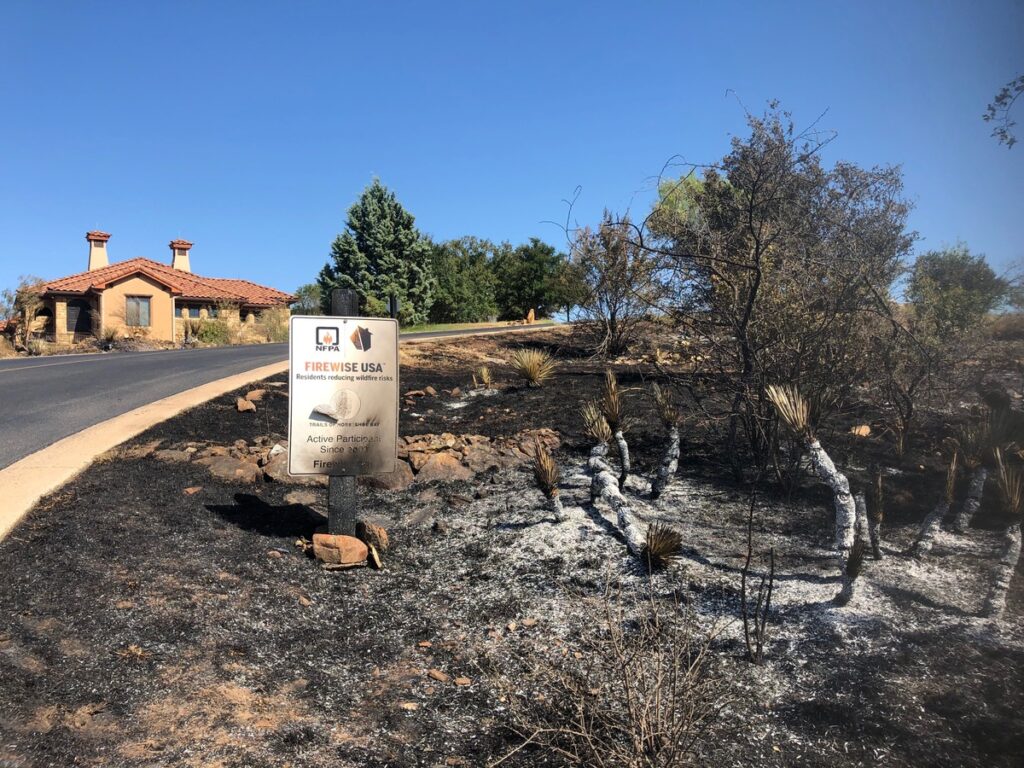 A burnt sign in a residential area after the Trails Fire