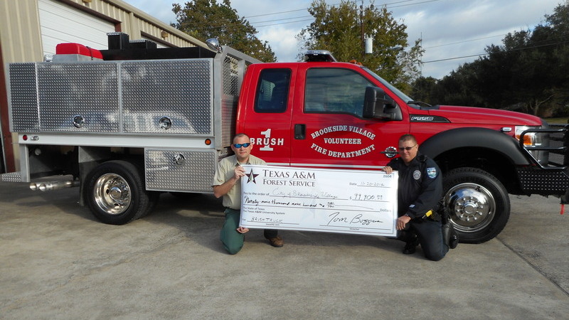 Brookside fire department members holding a big check in front of a newly donated truck
