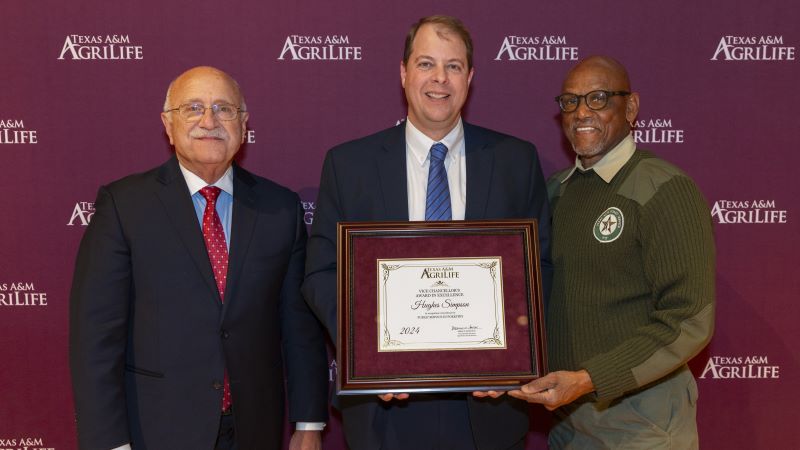 Jeff Savell, Hughes Simpson, and Al Davis stand holding a framed award