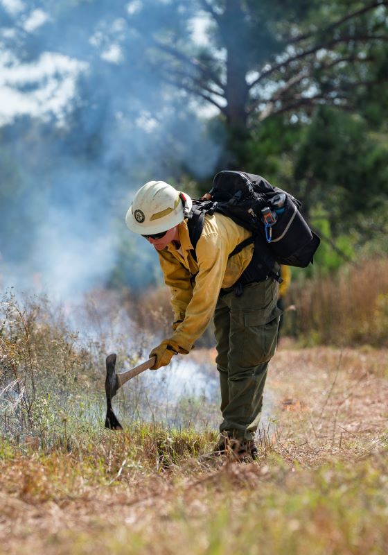Firefighter using handtool with smoke in the background
