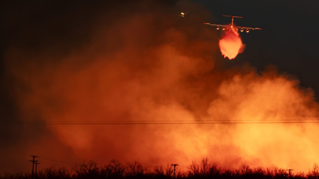 Plane makes a drop over large orange fire