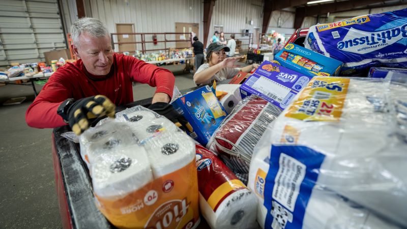 Man in red shirt pulls paper towels out of large stack