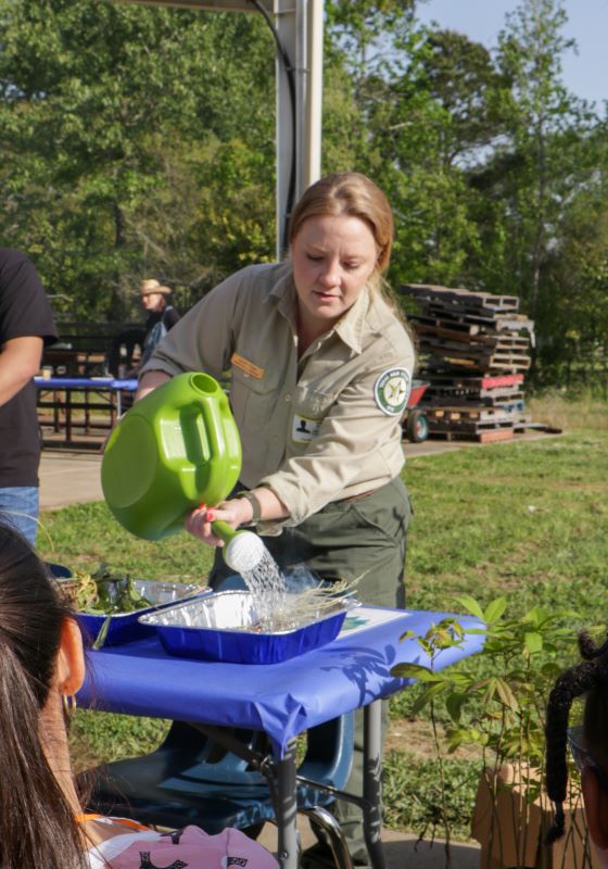 Forester pouring water from a pitcher for demonstration