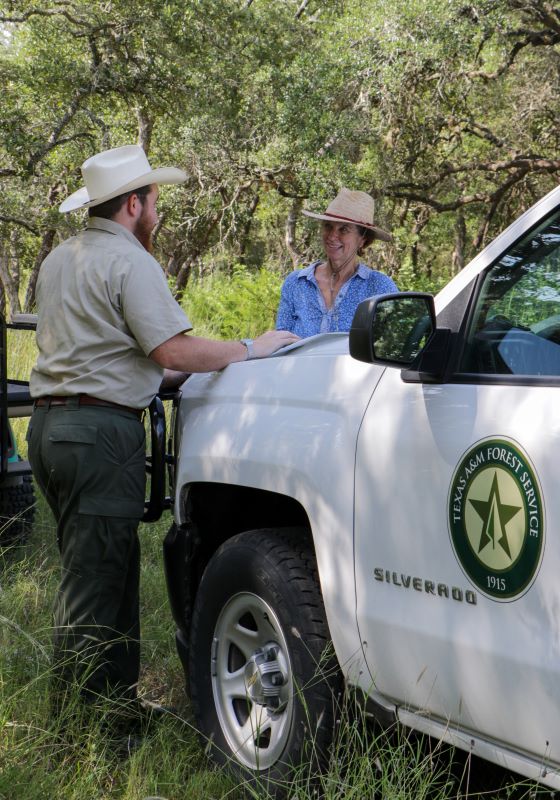 Forester talks to woman in blue shirt in front of Texas A&M Forest Service Leadership Institute