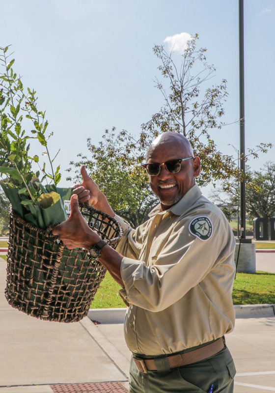Forester holds basket full of tree seedlings and smiles