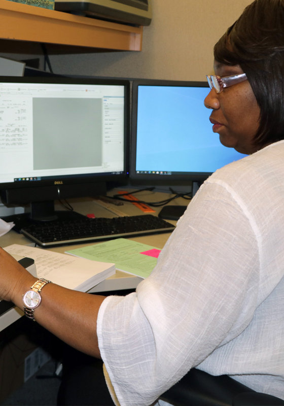 Woman sits at desk with multiple screens