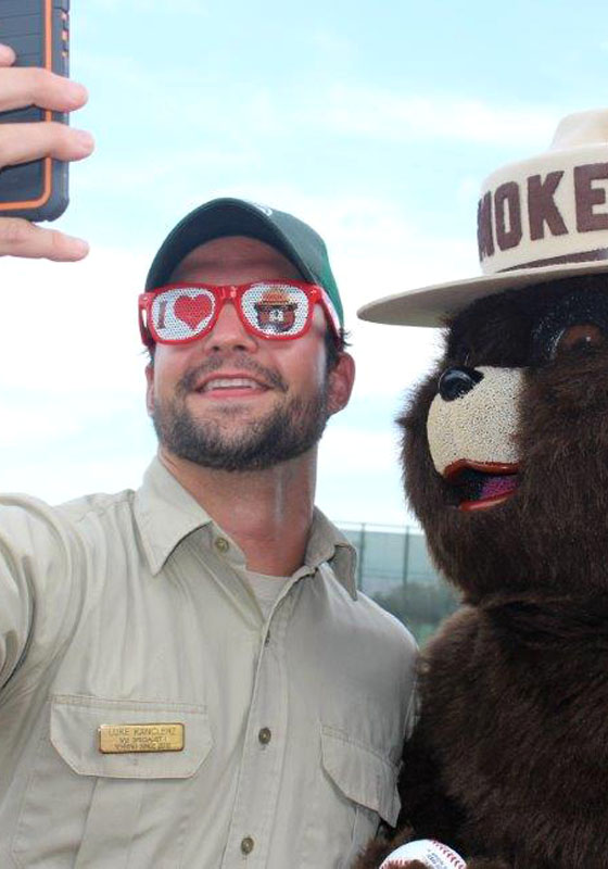 Forester with sunglasses on takes selfie with Smokey Bear