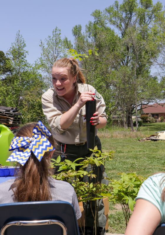 Forester teaching young children holding tree