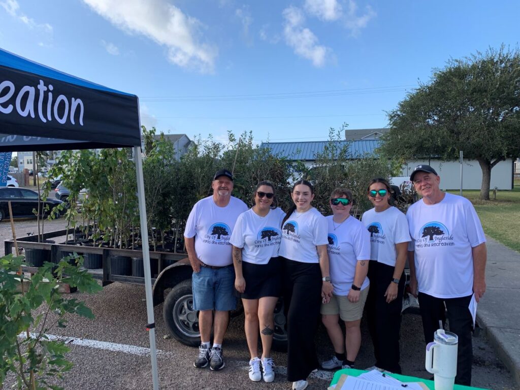Group of people standing in front of a trailer with trees on it