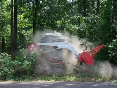 A red and white forestry mulcher in action mulching an area of land